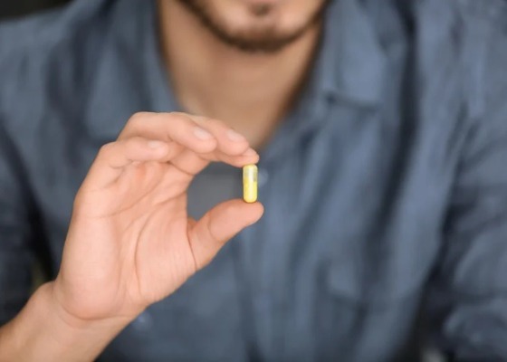 Man holding a bottle of HR23+ hair growth capsules 