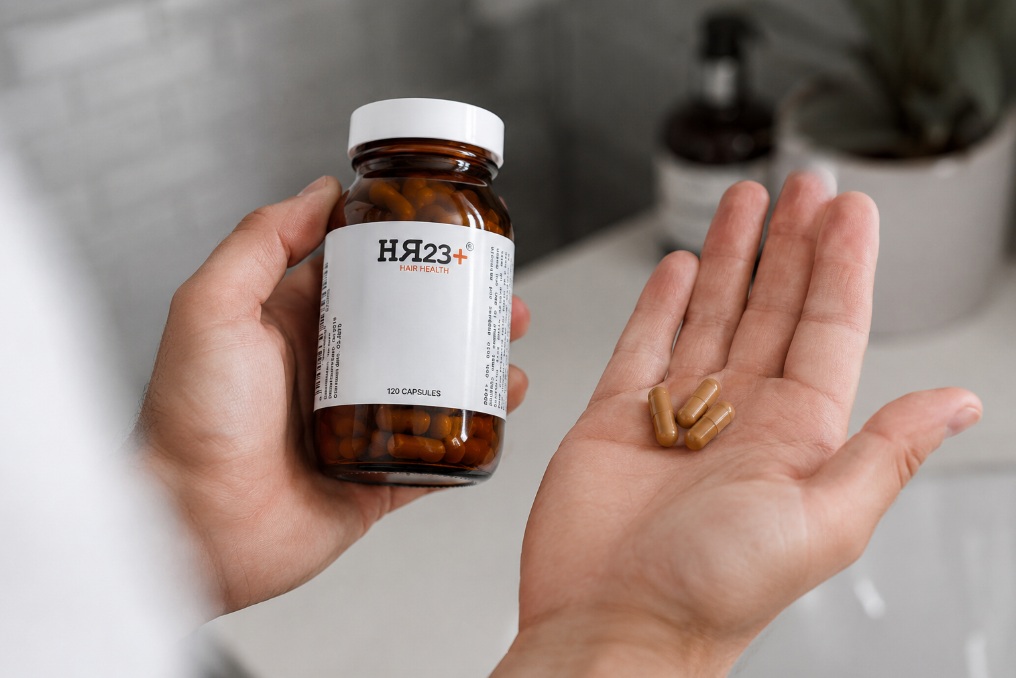HR23+ hair support capsules held in hand